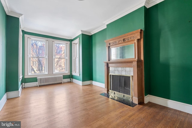 unfurnished living room with crown molding, hardwood / wood-style flooring, radiator, and a premium fireplace