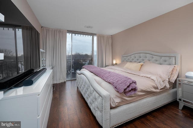 bedroom with dark hardwood / wood-style floors and floor to ceiling windows