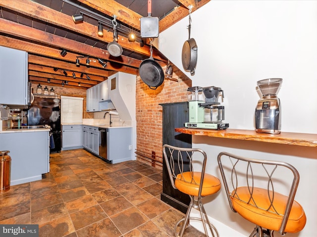 kitchen with sink, beamed ceiling, wood counters, stainless steel dishwasher, and brick wall