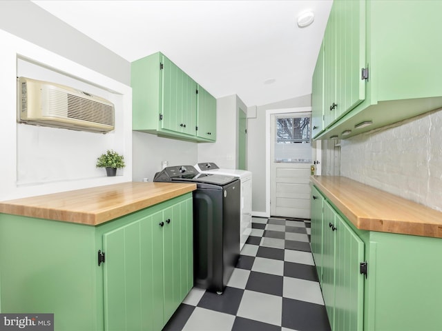 washroom featuring cabinets, washer and clothes dryer, and a wall unit AC