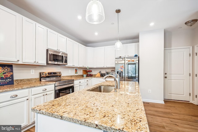 kitchen with sink, stainless steel appliances, white cabinetry, and decorative light fixtures