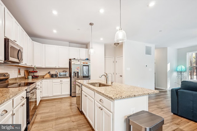 kitchen featuring pendant lighting, stainless steel appliances, an island with sink, white cabinets, and sink