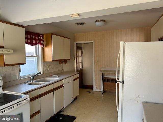 kitchen with sink, white cabinets, white appliances, and decorative backsplash