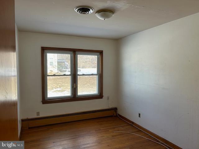 unfurnished room featuring a baseboard radiator and hardwood / wood-style floors