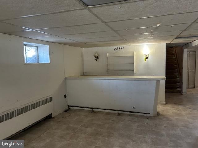 basement featuring radiator heating unit and a drop ceiling