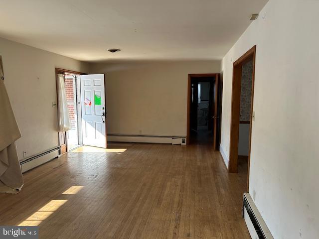 empty room with a baseboard heating unit and hardwood / wood-style flooring