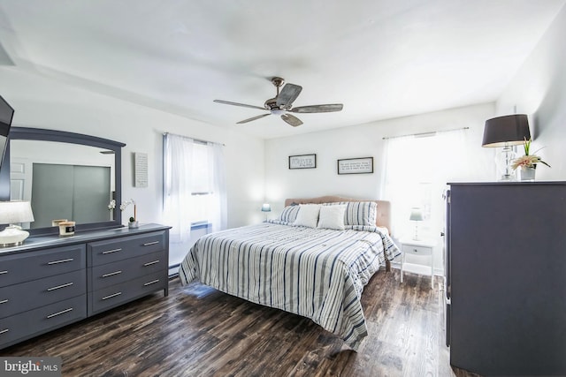 bedroom with dark hardwood / wood-style flooring, a baseboard heating unit, and ceiling fan