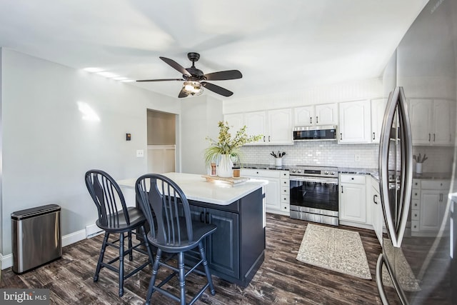 kitchen featuring a kitchen breakfast bar, appliances with stainless steel finishes, a center island, white cabinetry, and backsplash