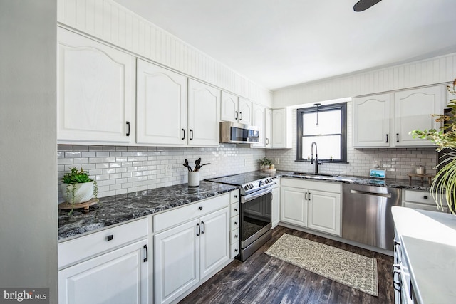 kitchen featuring appliances with stainless steel finishes, dark wood-type flooring, sink, white cabinetry, and tasteful backsplash