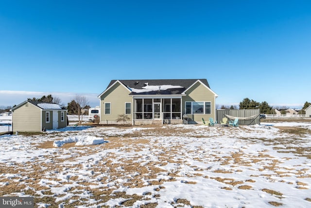 snow covered back of property featuring a sunroom