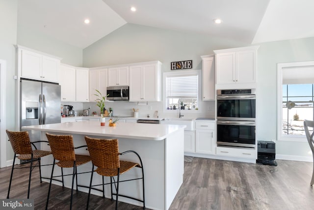 kitchen featuring hardwood / wood-style flooring, white cabinets, appliances with stainless steel finishes, and a kitchen island