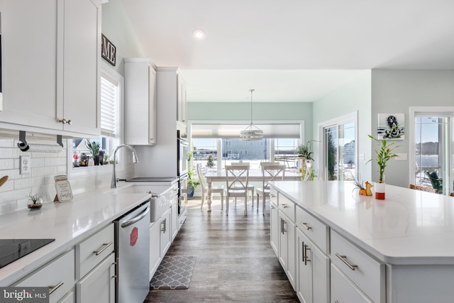 kitchen with a center island, pendant lighting, sink, stainless steel appliances, and white cabinets