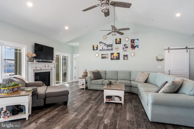 living room with ceiling fan, dark hardwood / wood-style flooring, lofted ceiling, and a barn door