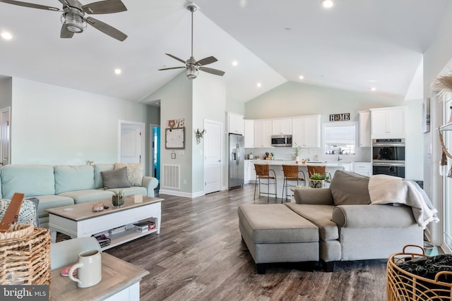 living room with dark wood-type flooring, ceiling fan, and high vaulted ceiling