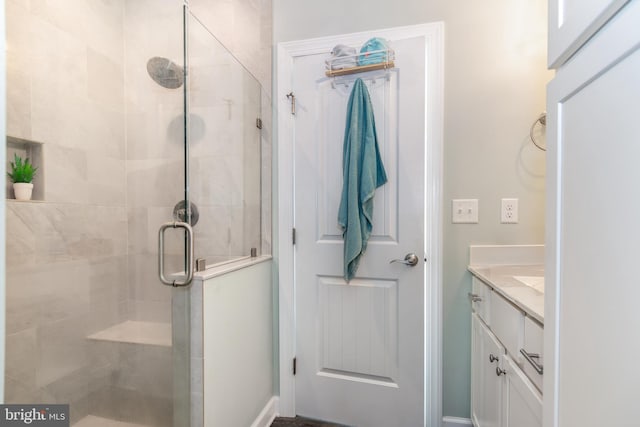 bathroom featuring a shower with shower door and vanity