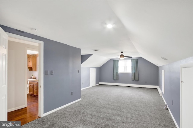 additional living space featuring lofted ceiling, dark carpet, and baseboard heating