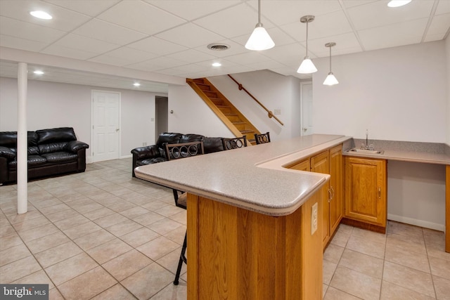 kitchen featuring pendant lighting, sink, a breakfast bar area, light tile patterned flooring, and kitchen peninsula