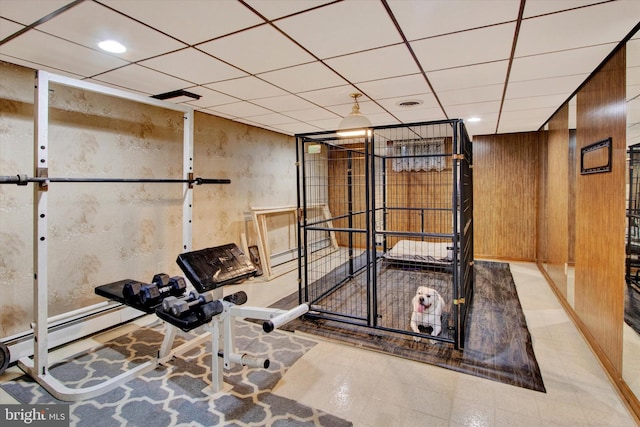 exercise area featuring a paneled ceiling and wood walls