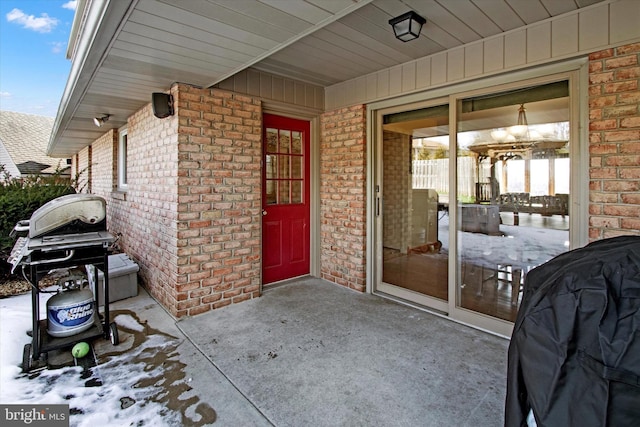 snow covered property entrance featuring a patio