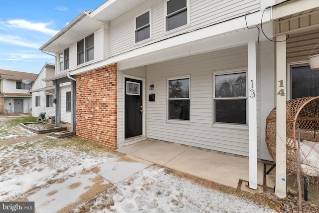 snow covered property entrance with a patio