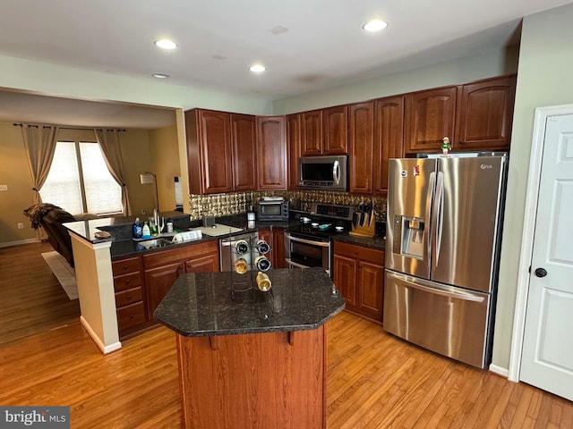 kitchen with a center island, tasteful backsplash, dark stone counters, appliances with stainless steel finishes, and sink