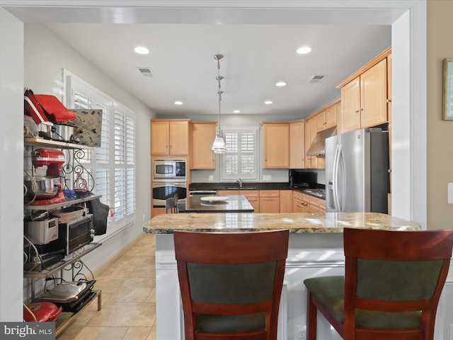 kitchen featuring light brown cabinetry, plenty of natural light, hanging light fixtures, and appliances with stainless steel finishes