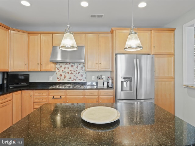 kitchen featuring dark stone countertops, appliances with stainless steel finishes, hanging light fixtures, light brown cabinets, and exhaust hood