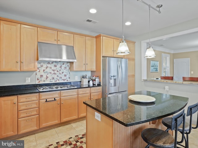 kitchen with dark stone counters, stainless steel appliances, a kitchen bar, and tasteful backsplash