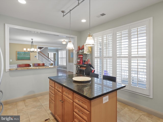 kitchen with dark stone counters, a notable chandelier, decorative light fixtures, and light tile patterned floors