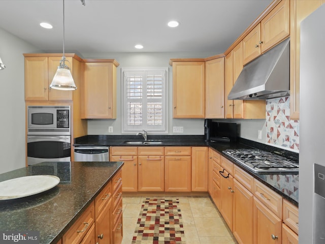 kitchen featuring sink, dark stone countertops, light tile patterned floors, pendant lighting, and appliances with stainless steel finishes