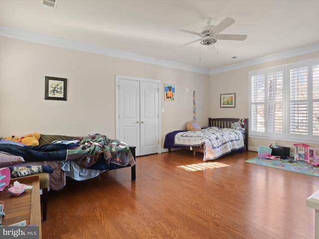 bedroom featuring ceiling fan, ornamental molding, a closet, and wood-type flooring