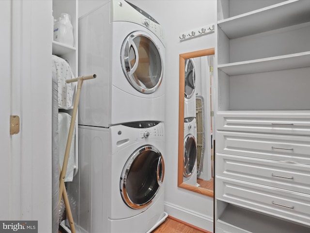 laundry room featuring stacked washer and clothes dryer and light hardwood / wood-style flooring