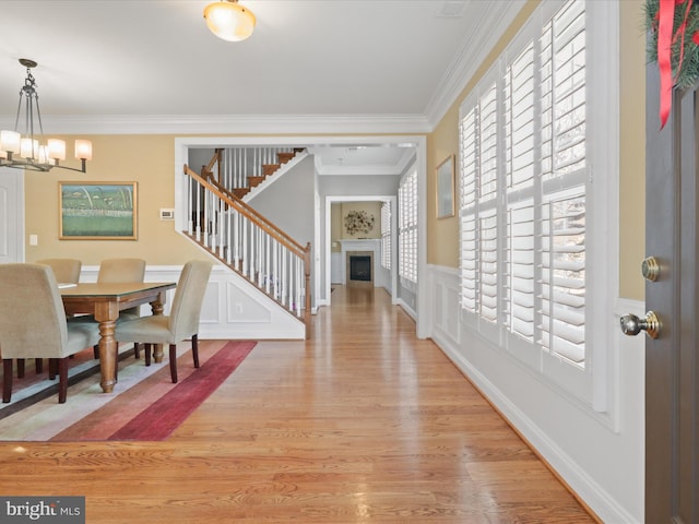 interior space featuring light wood-type flooring, an inviting chandelier, and crown molding