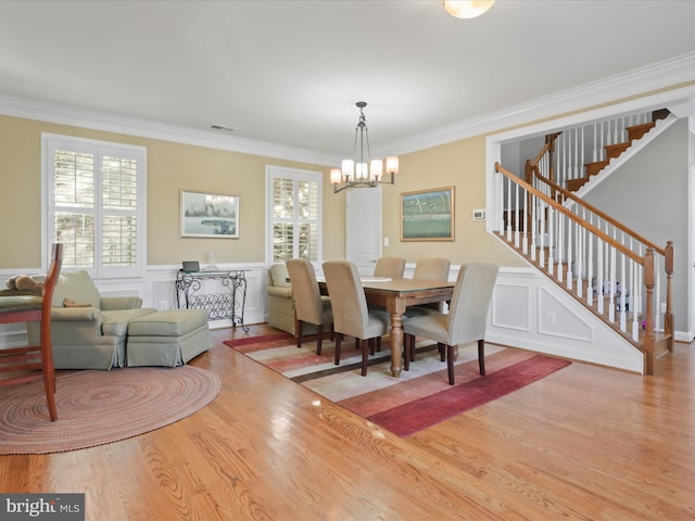 dining room with a notable chandelier, light wood-type flooring, and crown molding