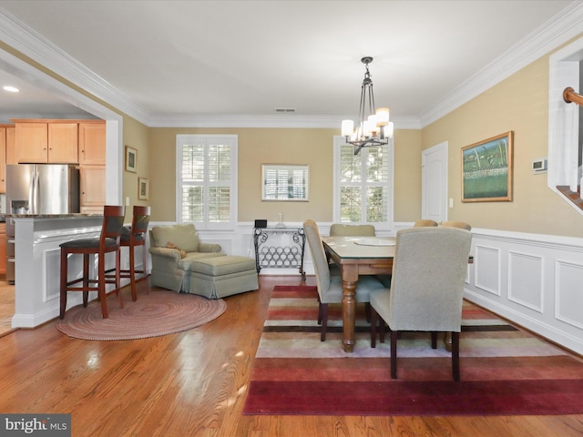 dining room with ornamental molding, hardwood / wood-style floors, and a chandelier