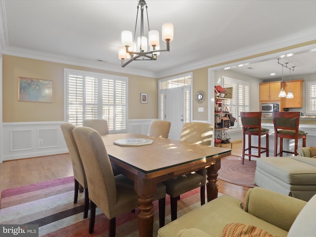 dining area featuring a chandelier, ornamental molding, and light hardwood / wood-style floors