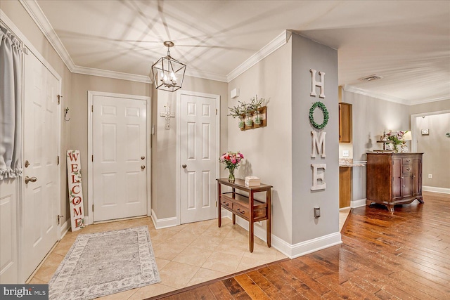 foyer featuring crown molding, light hardwood / wood-style floors, and a notable chandelier