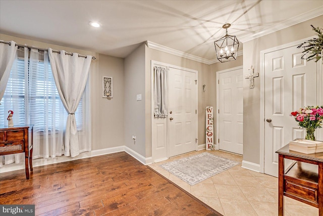 entrance foyer with ornamental molding, a chandelier, and light wood-type flooring