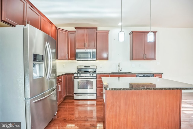 kitchen with pendant lighting, a center island, sink, hardwood / wood-style flooring, and stainless steel appliances