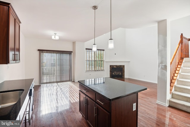 kitchen with a center island, hanging light fixtures, a high end fireplace, wood-type flooring, and dark brown cabinets