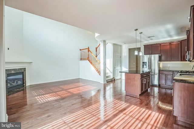 kitchen featuring appliances with stainless steel finishes, decorative light fixtures, a fireplace, dark hardwood / wood-style floors, and a kitchen island