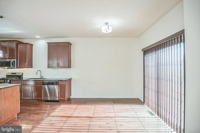 kitchen with appliances with stainless steel finishes, light hardwood / wood-style floors, and sink