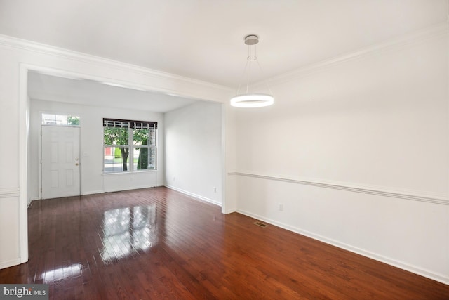 empty room with dark hardwood / wood-style floors and crown molding