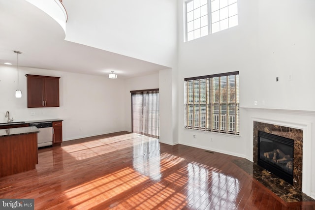 unfurnished living room with sink, a high end fireplace, and dark wood-type flooring