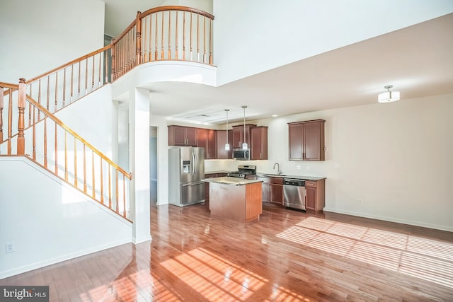 kitchen with hardwood / wood-style floors, a kitchen island, decorative light fixtures, and appliances with stainless steel finishes