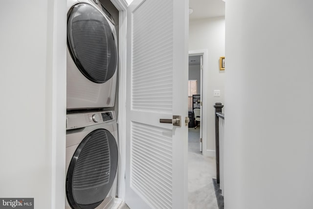 washroom with carpet, stacked washer and clothes dryer, and laundry area