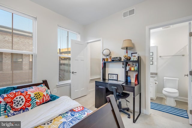 bedroom with baseboards, visible vents, and ensuite bathroom