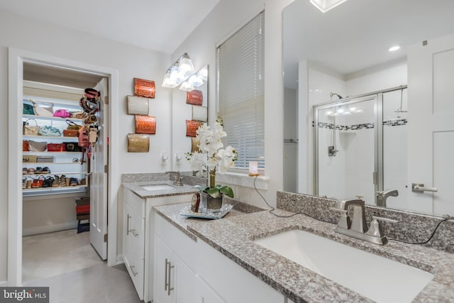 bathroom with double vanity, a shower stall, and a sink