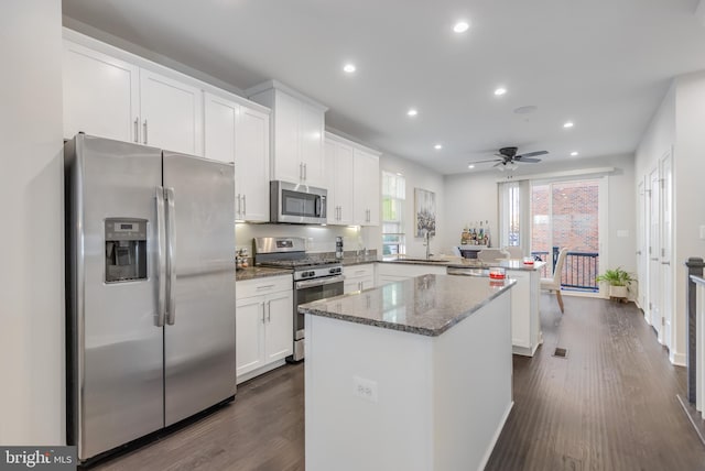 kitchen featuring a sink, stainless steel appliances, a peninsula, and white cabinetry