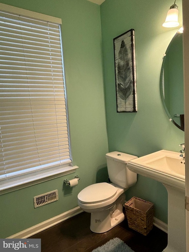 bathroom featuring toilet, a healthy amount of sunlight, and wood-type flooring